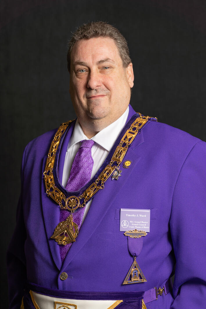 man in purple suit with black background headshot