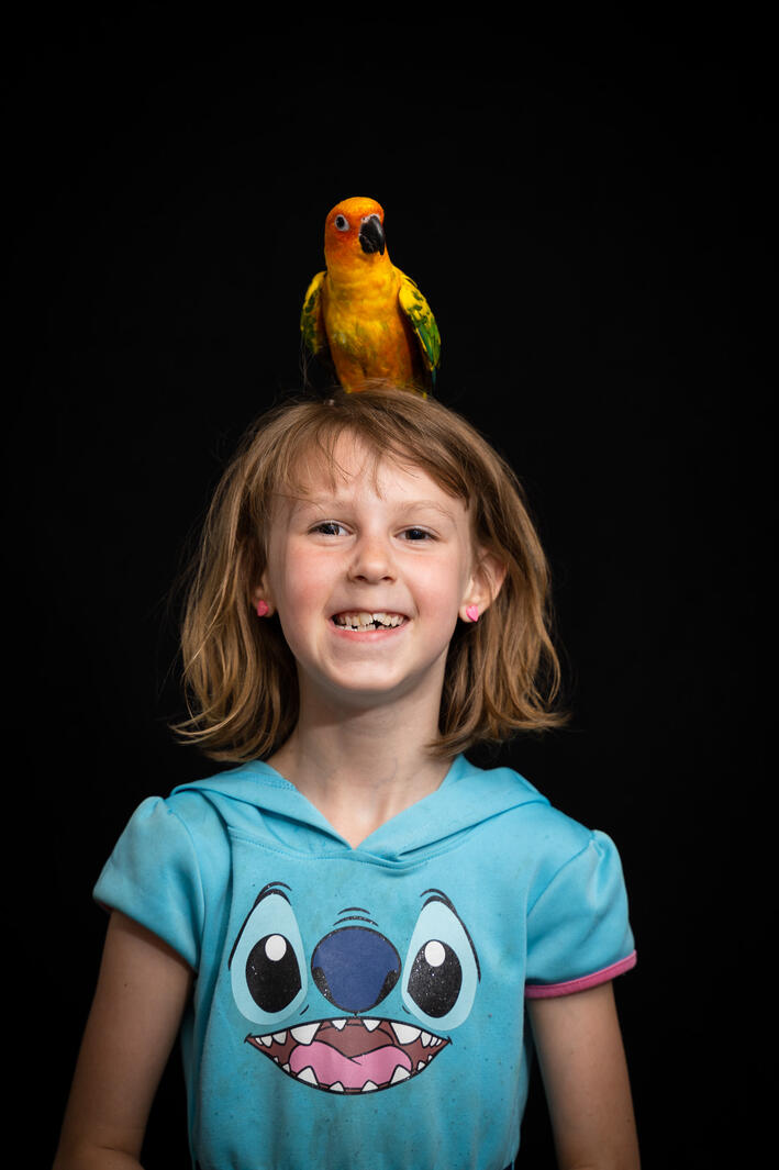 girl with bird on head and black background