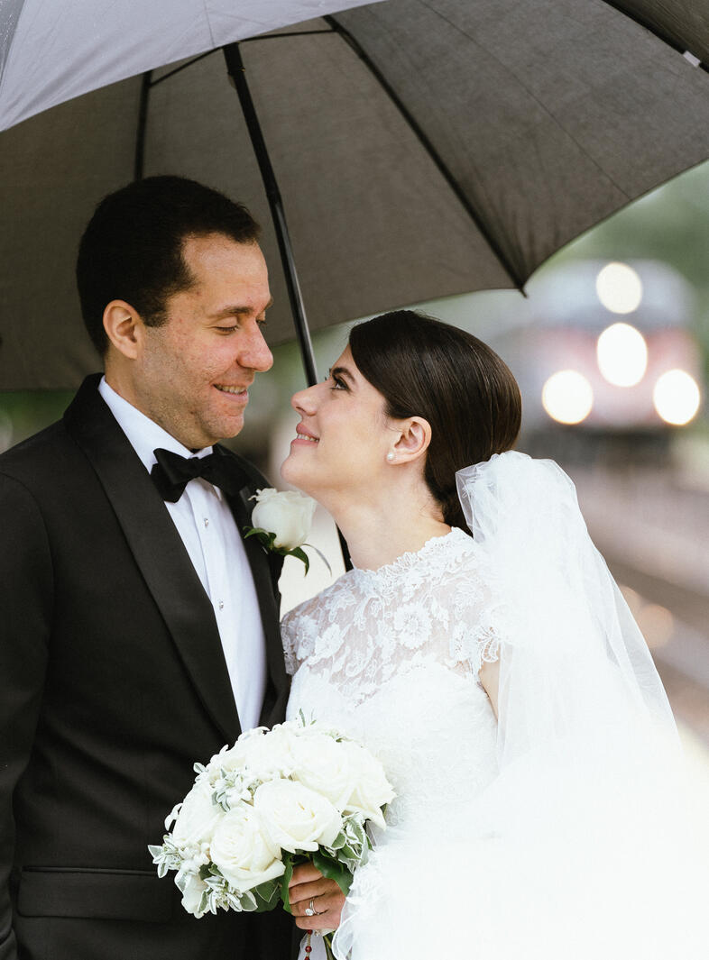 man and woman at train station with umbrella wedding